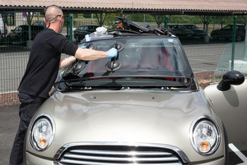Person installing a windshield on a sports car in Norwalk.