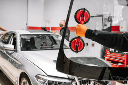 Person using a dual suction lifter preparing to install a new windshield on a card.