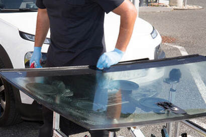 Person preparing a windshield for installation on a car in Norwalk.
