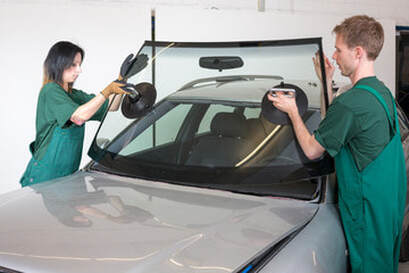 Two people installing a new windshield on a car in Norwalk, CT.