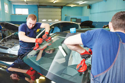 Two people installing a front windshield on a vehicle in Norwalk, CT.